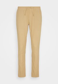 Pantalon beige décontracté coupe ajustée avec taille élastique et cordon de serrage, poches avant et détails cousus le long des jambes.