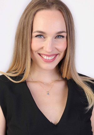 Des colliers en or superposés, ornés d'un pendentif avec une pierre précieuse noire. Le mannequin porte un chemisier noir avec un décolleté en V.