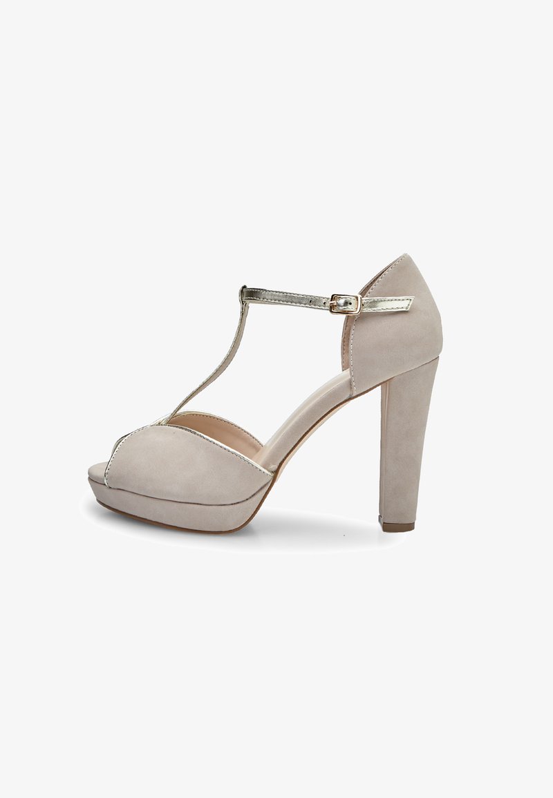 Bež čevelj na visoki peti z obliko T-spona, iz süda, odprtega prsta in kovinskim poudarkom na sponki. Debela platforma in trdna peta.