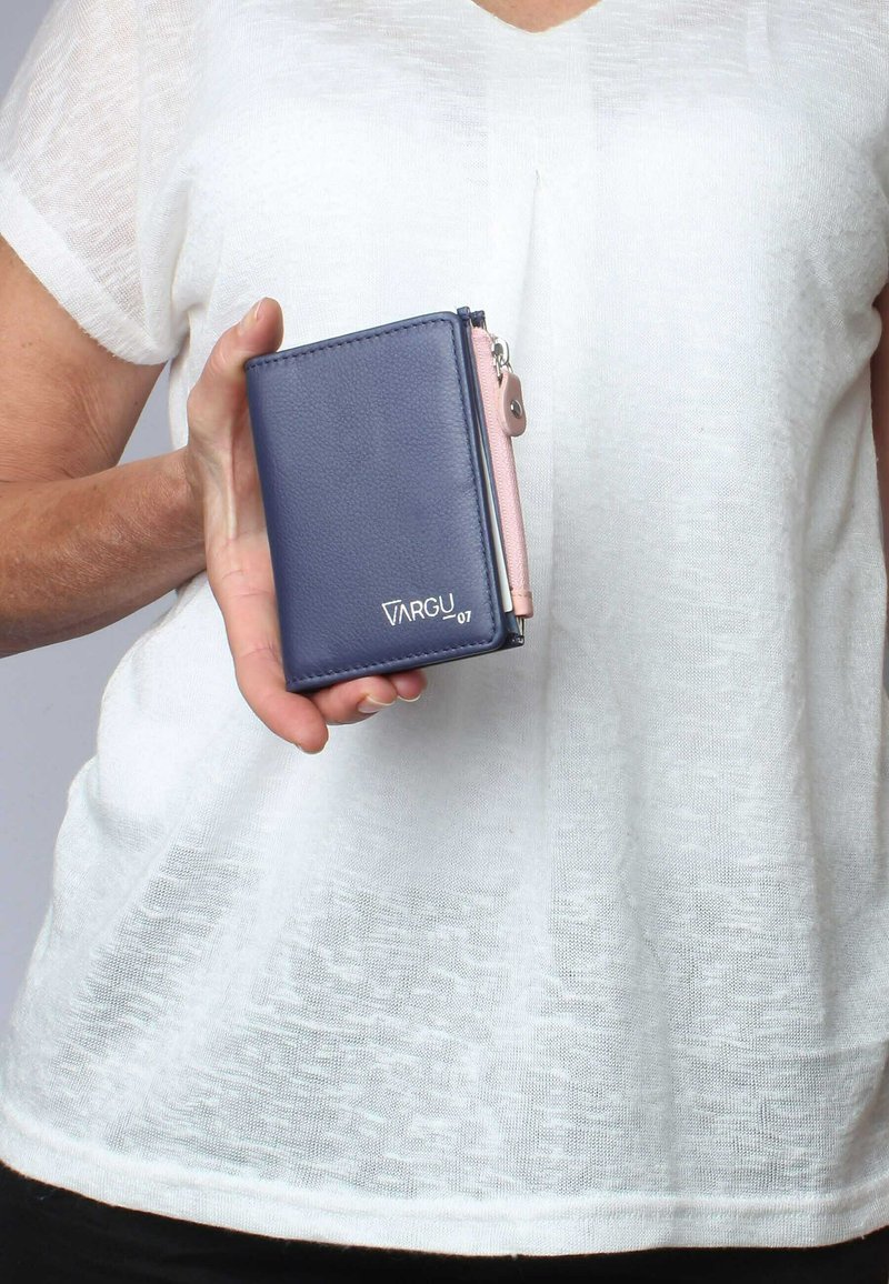 Dunkelblaues Wallet aus strukturiertem Material, mit einem pinkfarbenen Reißverschluss, Logo auf der Vorderseite geprägt, kompakte rechteckige Form.