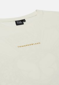 Lichtbeige katoenen T-shirt met een ronde hals, voorzien van gouden geborduurde tekst "TOMORROWLAND" op de voorkant en een zachte textuur.