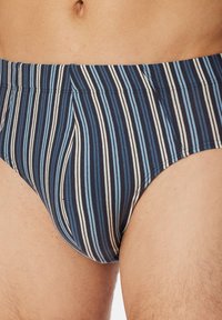 Caleçons de bain rayés en bleu marine et bleu clair avec des accents blancs. Ils présentent une ceinture élastique confortable et une texture de tissu lisse.