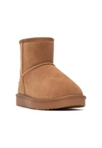 Bota de tobillo de ante marrón claro con punta redonda, detalles de costura mínimos y suela de goma con un patrón texturizado para mayor adherencia.