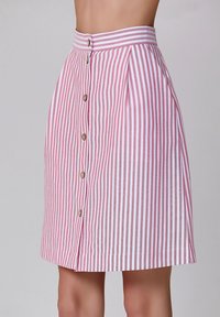 Une jupe rayée rose et blanche à taille haute, dotée d'une fermeture à boutons sur le devant et de plis, fabriquée en tissu léger.