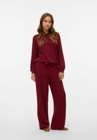 Bordeaux tweed set met een langemouwen top met elastische manchetten en een broek met wijde pijpen en een trekkoord in de taille voor een verstelbare pasvorm.