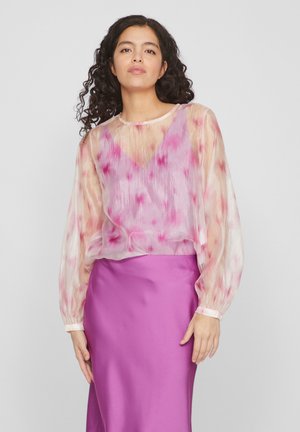 Blouse en voile avec un dégradé pastel rose et blanc, présentant des manches bouffantes et un col rond. Assortie à une jupe en satin violet uni.