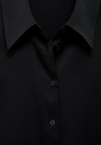 Czarna koszula typu button-up z wykrojem kołnierza, charakteryzująca się gładką fakturą materiału i czterema czarnymi guzikami wzdłuż zapięcia.