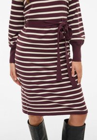 Knee-length kudumisega kleit burgundi ja kreemjastriibulises mustris, mis sisaldab sidumisvööd ja pikki varrukasid ribakudumisega mansettidega. Pehme kudumise tekstuur.