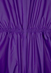 Tecido roxo com uma textura suave, apresentando elástico franzido na cintura e costuras verticais para estrutura.