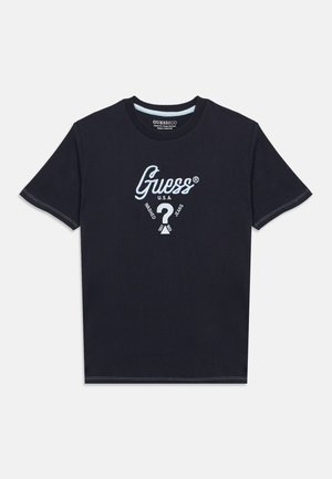 Musta lyhythihainen T-paita, jossa on vaaleansininen "Guess U.S.A." -logo, kysymysmerkki ja sana "Washed Jeans" painettuna rintapuolelle.