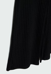 Zwarte geribde stof broek met een vloeiende uitstraling, met verticale lijnen en een uitlopende silhoeët. Zachte textuur, zoom valt lichtjes.