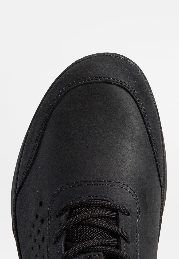 Czarny sneaker z gładką cholewką, okrągłym noskiem i teksturowanymi akcentami; posiada czarne sznurowadła i perforacje po bokach dla lepszej wentylacji.