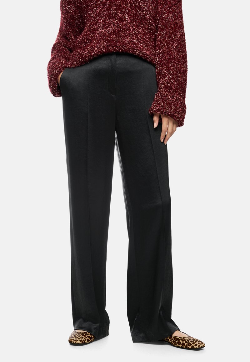 Black, wide-leg pants made of smooth fabric with a slight sheen. Paired with a red textured knit sweater and leopard print flats.