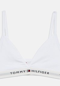 Λευκό βαμβακερό bralette με λεπτές τιράντες και τριγωνικό σχέδιο, με ελαστική ταινία με το εμπορικό σήμα που αναγράφει "TOMMY HILFIGER" σε μαύρο.