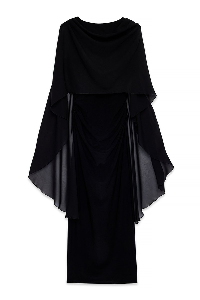 Melna kleita ar plūstošu caurspīdīgu audumu, kas novilkts virs pieguļoša bodycon slāņa. Iezīmēta ar noapaļotu kakla izgriezumu un arrušanās detaļām Jostas vietā.