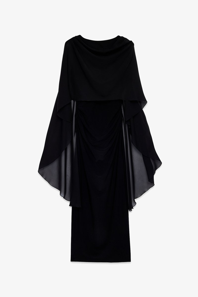 Črna obleka z tekočim prosojnim materialom, ki je narejen nad oprijetim bodycon slojem. Ima okroglo izreza in naborke pri pasu.