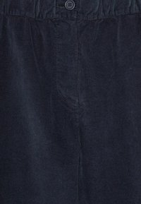 Tessuto di velluto a coste scuro con una trama a coste, dotato di chiusura con bottone in vita e design dei pantaloni a gamba dritta.