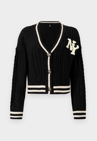 Musta cable-knit neuletakki V-pääntiellä, vaaleanbeige raidallinen viimeistely, kolme suurta nappia ja brodeerattu "NY" vasemmassa rinnassa.