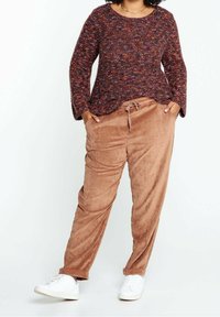 Tjock, strukturerad vinröd tröja med vida ärmar och rundad nederkant, kombinerad med mjuka, sandbruna kordflöjlsbyxor med dragsko.