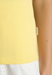 Kohvitooted kollane tank-top pehmest kangast, küljes sildiga "Joules". Heljandi ääred on lõppviimistlusega.