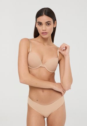Reggiseno imbottito beige con coppe lisce, sottili spalline regolabili e design senza cuciture. Abbinato a slip bikini a vita bassa coordinati.