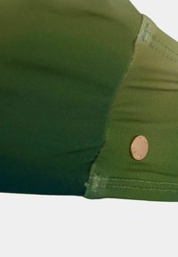 Top da bagno con gradiente verde caratterizzato da una texture liscia e un piccolo dettaglio in metallo sul lato. La cucitura è visibile.