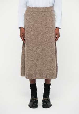 Kootud seelik tekstuuriga pruunist kangast, keskmise sääre pikkusega ja vooderdatud vöökoht. Koos mustade kihiliste sokkide ja loaferitega.