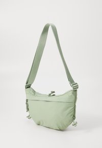 Helle grüne Schultertasche aus Nylon, mit weichem, gepolstertem Design, verstellbarem Träger und Schleifen-Detail an der Oberseite. Enthält eine Reißverschlusstasche.