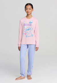 Maglietta da pigiama a maniche lunghe rosa con stampa di personaggi dei cartoni animati blu, abbinata a pantaloni azzurri chiari con accenti colorati di stelle e fiori.