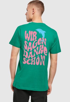 Grünes Baumwoll-T-Shirt mit verspielter rosa Blasenschrift und einem blauen Delfin auf dem Rücken, Rundhalsausschnitt und kurzen Ärmeln.