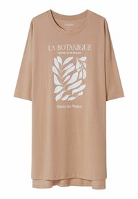 Oversized beżowy t-shirt z białą ilustracją botaniczną i francuskim tekstem "La Botanique Galerie de la Nature Beauté des Plantes" z przodu.