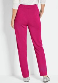 Fuchsia broek met een getailleerde pasvorm, hoge tailleband en verborgen voorzakken; gladde stofafwerking; enkellang met minimale stikseldetails.