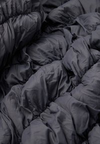 Σκοτεινό γκρι μονωτικό κουβέρτα με υφή γεμισμένου. Φέρει πλούσιες περιοχές και ελαστικούς συγκρατητές, κατασκευασμένο από μαλακό, λείο ύφασμα.