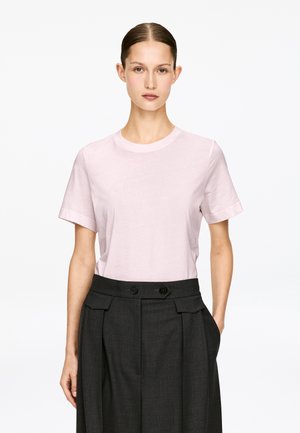 Light pink short-sleeve t-shirt with a round neckline, paired with dark gray high-waisted trousers featuring front pleats and double button closure.