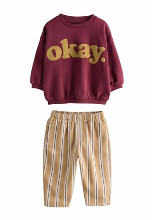 Sudadera de manga larga color burdeos con texto amarillo "okay.", combinada con pantalones beige y blancos a rayas verticales con cintura elástica.