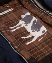 Forro xadrez castanho com uma grande gráfica de uma vaca branca e preta. Detalhe de zipper ao longo da borda. O tecido exterior é de uma cor sólida escura.
