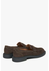 Brown suede loafers with a rounded toe, decorative stitching, and a thick black rubber sole. Features a slip-on design and textured accents.