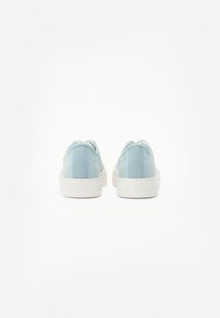 Sneakers in tela azzurro chiaro con suole in gomma bianca. Design semplice con una finitura texturizzata e branding minimale sul tallone.