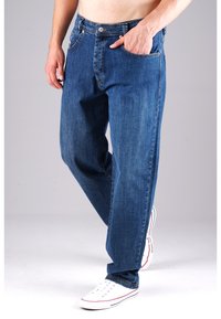 Blaue Jeans aus Denim mit geradem Bein, fünf Taschen, Kupferbeschlägen und Kontrastnähten. Kombiniert mit weißen Sneakers.