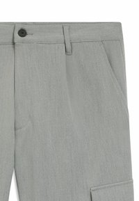 Close-up van lichtgrijze broek die de tailleband met knoop, riemlus, zijzak en een deel van een cargo-zak laat zien.