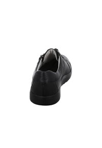Chaussure en cuir noir avec une surface texturée, un talon bas et une fermeture éclair à l'arrière. Design minimaliste avec un bout arrondi et une semelle noire solide.