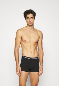 Boxer shorts en coton noir avec une ceinture élastique marquée "JACK & JONES" en texte blanc. Texture lisse et design ajusté.