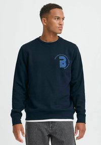 Navyblauer Sweatshirt aus weichem Stoff, mit rundem Halsausschnitt, langen Ärmeln und einem kleinen gestickten Logo auf der linken Brust.