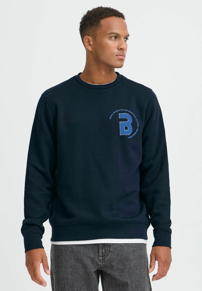 Navyblauer Sweatshirt aus weichem Stoff, mit rundem Halsausschnitt, langen Ärmeln und einem kleinen gestickten Logo auf der linken Brust.