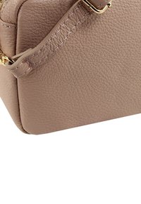 Eckiger hellbrauner Lederhandtasche mit strukturierter Oberfläche, goldenen Beschlägen und auffälligen Nähten. Glatte und klare Form.