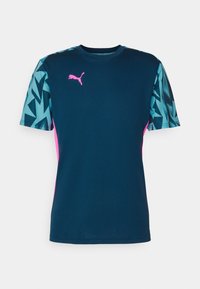 Námořnická modrá sportovní tričko s tyrkysovými geometrickými vzory na krátkých rukávech, růžovými detaily a růžovým logem Puma na hrudi.
