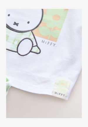Biała bawełniana koszulka z grafiką postaci Miffy z zielonymi akcentami, przeszyciami i metką z wzorem kwiatu.