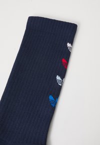 Navy ribbed socks with multicolored heart designs in red, white, and blue along the side; made of soft knit material.