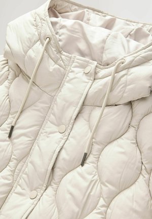 Doudoune beige clair avec un design matelassé, dotée d'une capuche, de cordons de serrage réglables et d'une fermeture à boutons-pression.