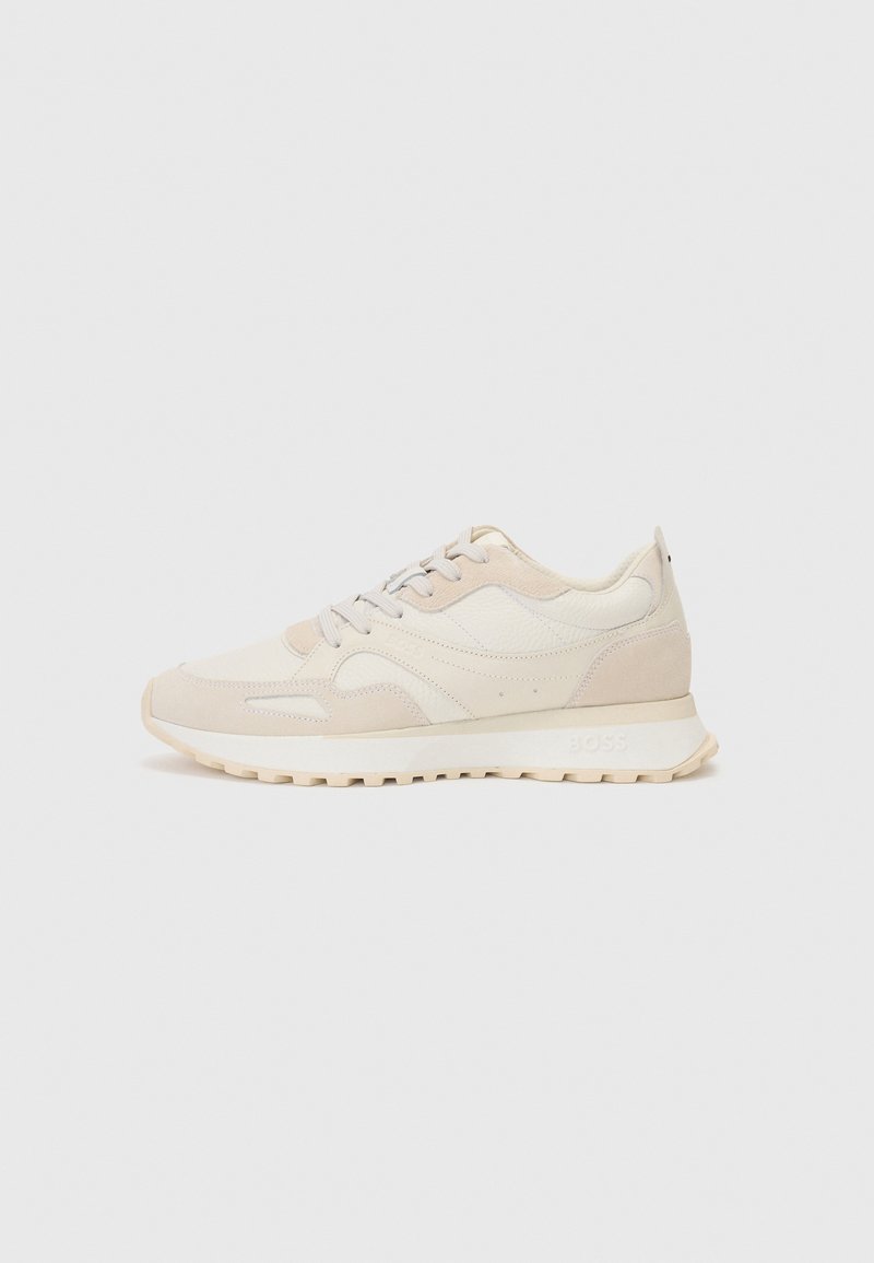 Baskets de sport beiges en daim et cuir. Elles présentent un bout rond, des lacets et des détails texturés. Semelle légère avec un motif de semelage.
